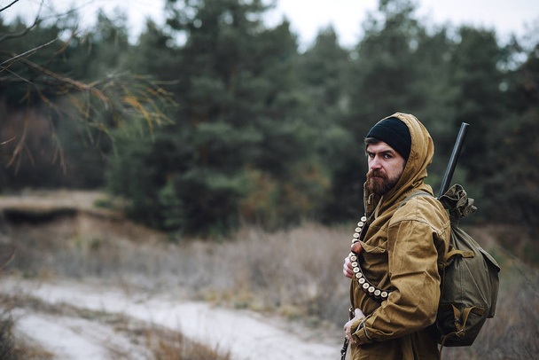 Бородатый охотник с профессиональным оборудованием прогулки по лесу
 - Фото, изображение