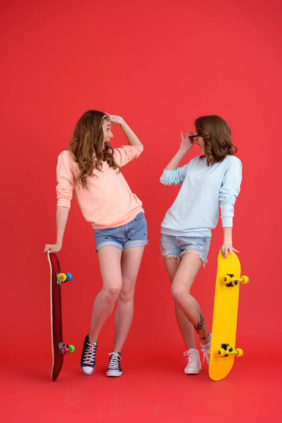 Amazing two ladies friends holding skateboards. - Zdjęcie, obraz