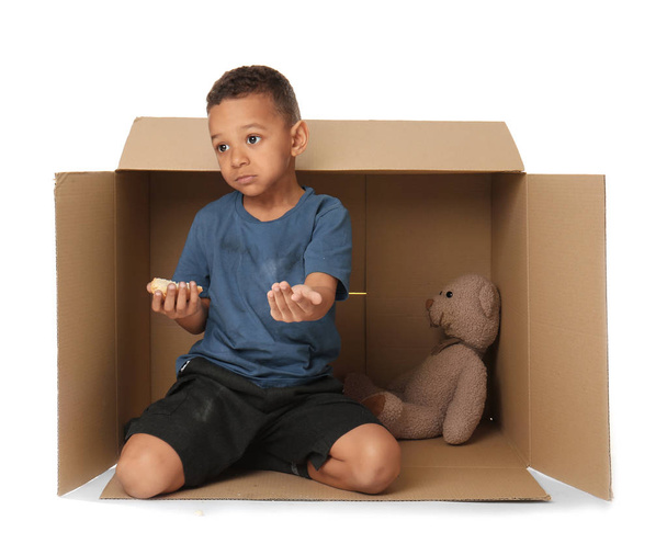 Cute little boy living in box on white background. Poverty concept - Foto, imagen