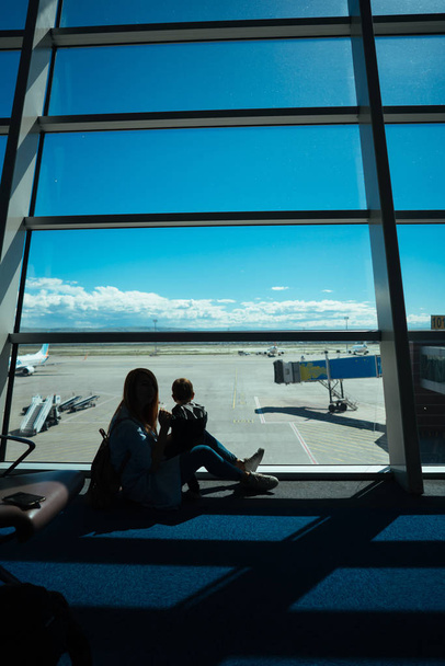 Niño y su madre sentados en un aeropuerto
 - Foto, Imagen
