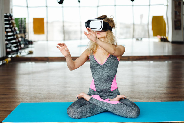 Женщина в классе йоги с VR гарнитурой
 - Фото, изображение