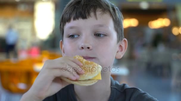 jongen eet een zwarte Hamburger close-up. - Video