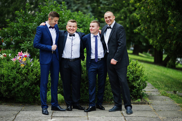 Four intelligent and handsome graduates in tuxedos posing on the - Fotografie, Obrázek