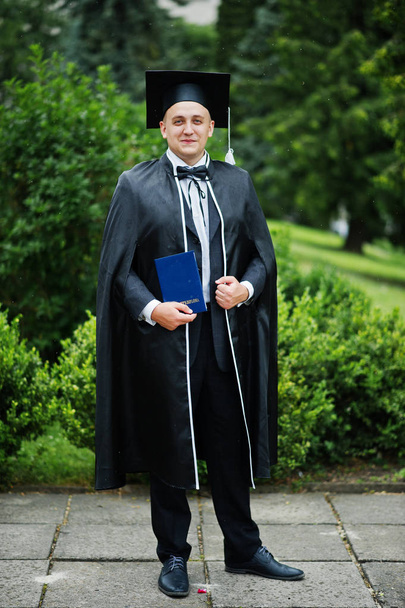 Portrait of an elegant young man in park dressed in graduation g - Photo, Image