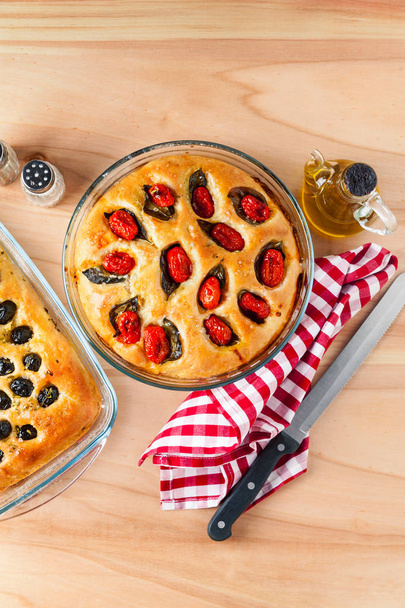 Two homemade Italian focaccia with olives and cherry tomatoes on - Fotografie, Obrázek