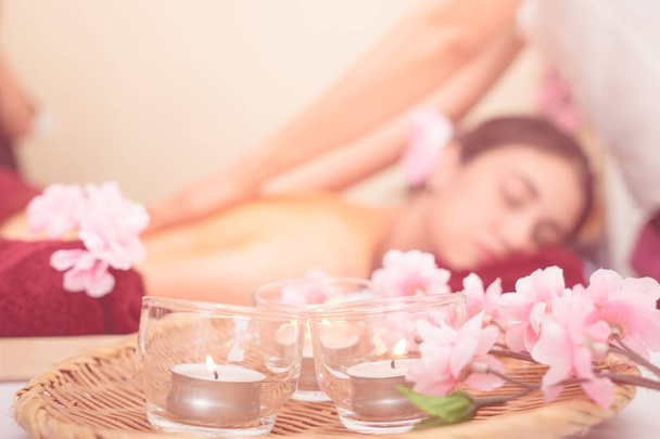 Women is getting massage in the background with Candles on the foreground. - Foto, imagen