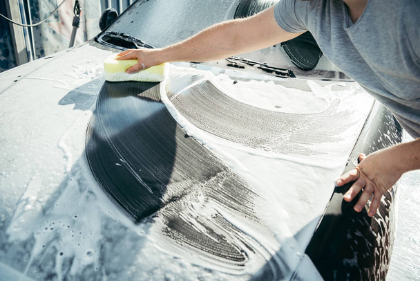 eine Hand wäscht ein Auto mit einem Schwamm - Foto, Bild