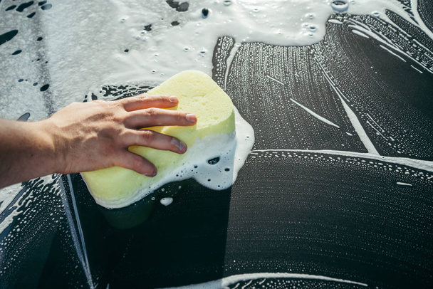 eine Hand wäscht ein Auto mit einem Schwamm - Foto, Bild