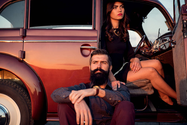 Stylish bearded man and pretty brunette sitting inside a luxurious car - Foto, afbeelding