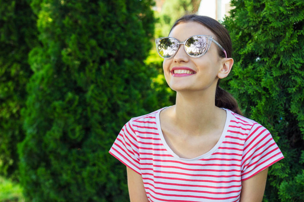 Красивая девушка в розовых солнечных очках на фоне парка
 - Фото, изображение