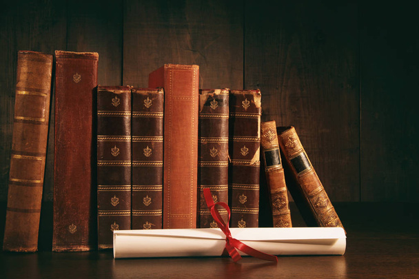 Куча старых книг с дипломом на столе
 - Фото, изображение