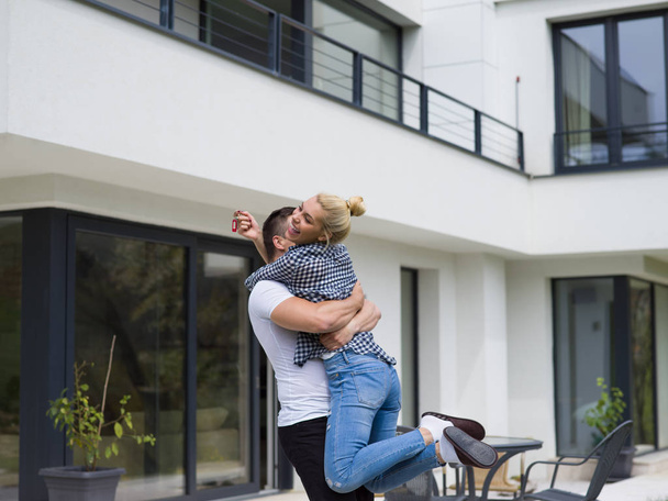 pareja abrazándose frente a una nueva casa de lujo
 - Foto, imagen