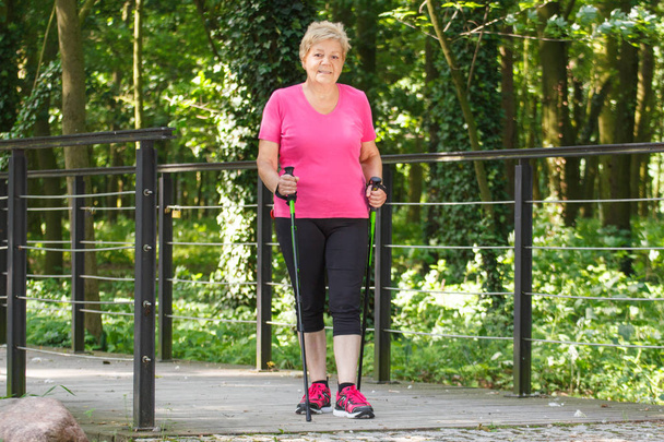 Elderly senior woman practicing nordic walking, concept of sporty lifestyles in old age - Foto, Imagem