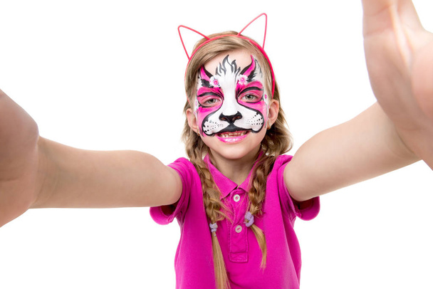 schattig klein meisje met geschilderde masker op gezicht selfie maken - Foto, afbeelding