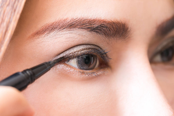 Close-up vrouwen make-up met zwarte en bruine eyeliner. - Foto, afbeelding