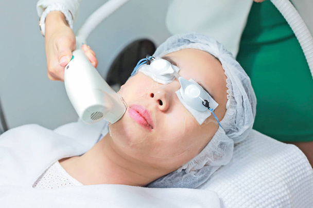 Nahaufnahme einer Kosmetikerin, die junge Menschen mit Laserepilation behandelt - Foto, Bild