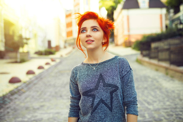 Young redhead woman looking up standing on the urban street - Фото, зображення