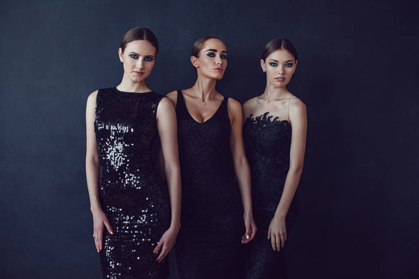 Attractive girls in black cocktail dresses on a dark background. - Photo, Image