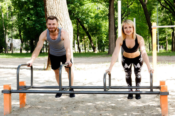 Young sportive woman and bearded man doing push-ups exercises in - Fotografie, Obrázek