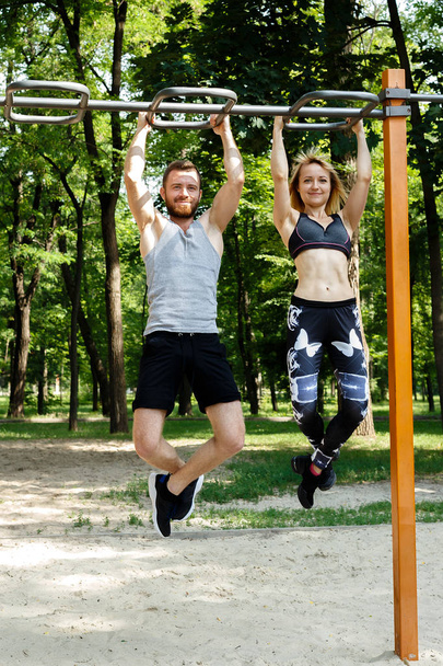 Giovane coppia sportiva che fa esercizi di pull-up sulla traversa in un
  - Foto, immagini