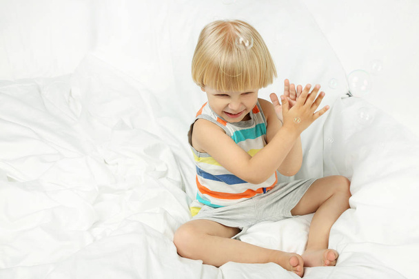 Little boy sitting in white bed - Фото, изображение