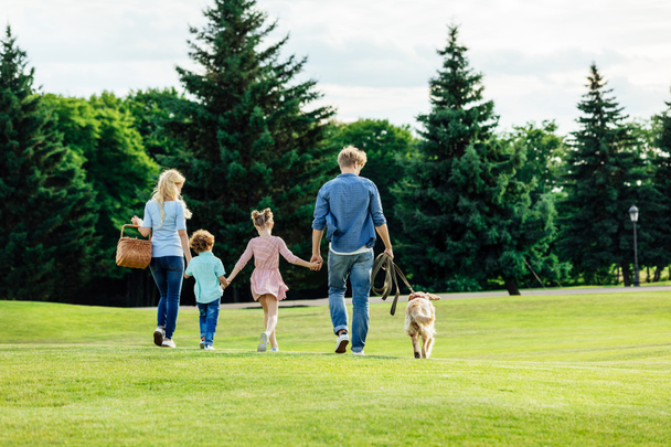 2 人の子供が公園で犬を連れて歩いて幸せな若い家族 ロイヤリティフリー写真 画像素材