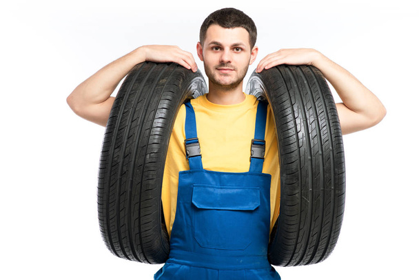 reparador en uniforme azul con neumáticos
 - Foto, Imagen