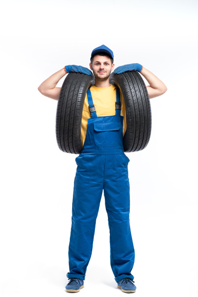 Reparaturhelfer in blauer Uniform mit Reifen - Foto, Bild