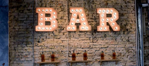 Inscription Bar of light bulbs against the wall of bricks - Zdjęcie, obraz