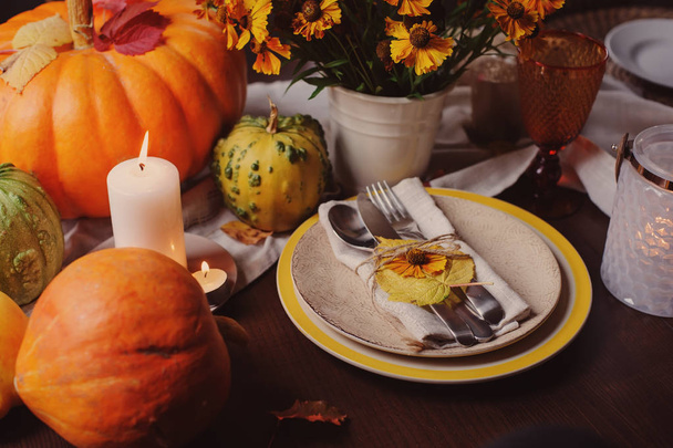 autumn traditional seasonal table setting at home with pumpkins, candles and flowers. Family celebrating Thanksgiving day. - Фото, изображение