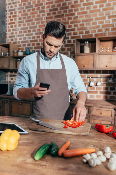 man using smartphone while cooking - Foto, Bild