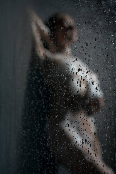Sexy model posing nude in shower behind the glass - Photo, Image