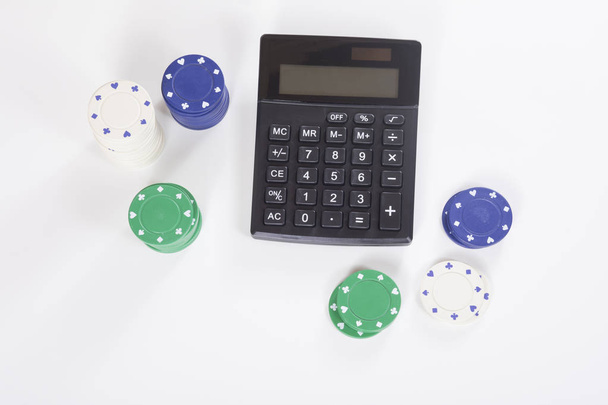 Calculadora rodeada de fichas de póquer surtidos
 - Foto, Imagen