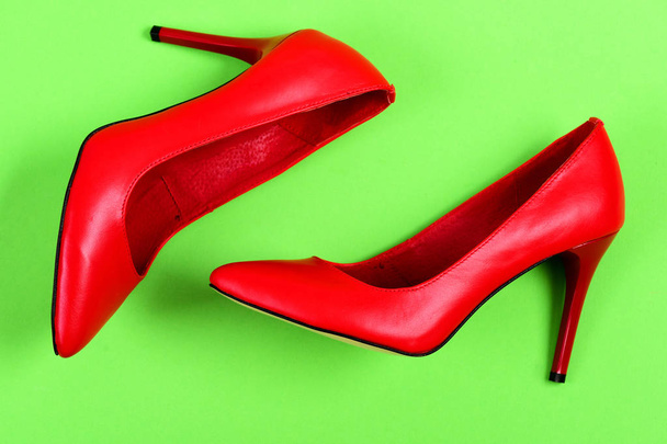 Pair of red leather high heel shoes on green background - 写真・画像