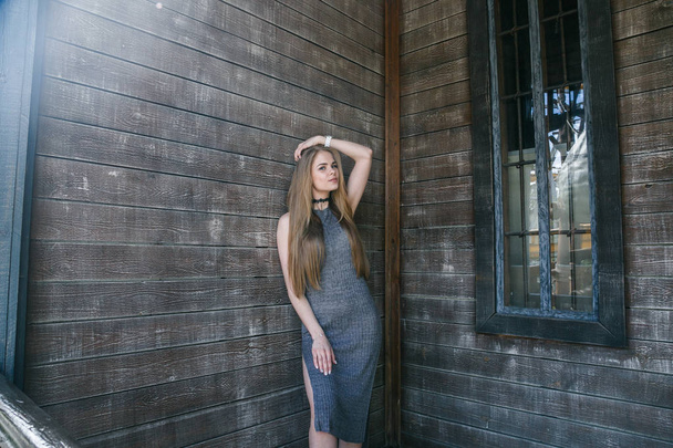 Model in grey dress in front of wooden wall - Valokuva, kuva