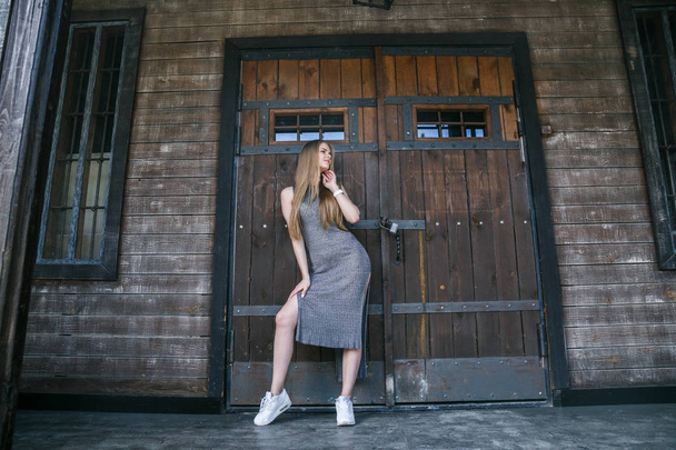 Model in grey dress in front of wooden building - Valokuva, kuva