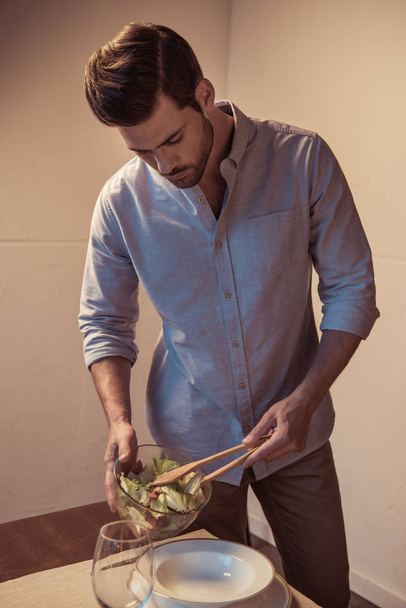 man putting salad on plate - Fotoğraf, Görsel