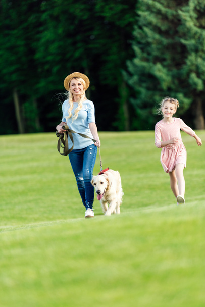 mother and daughter with dog in park - Фото, изображение