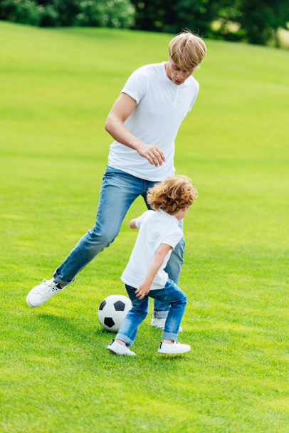 father and son playing soccer in park - Fotoğraf, Görsel