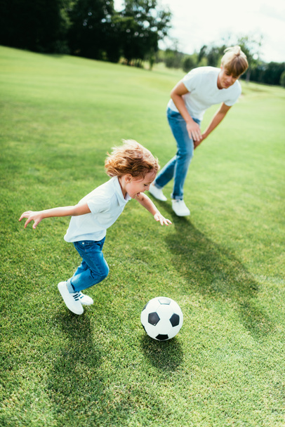 father and son playing soccer in park - Photo, Image