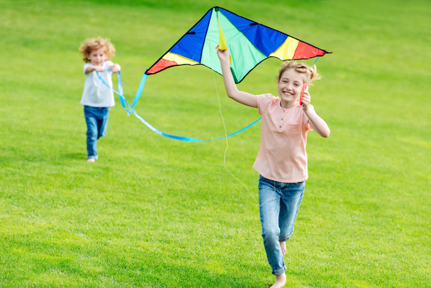 siblings playing with kite at park - Фото, изображение