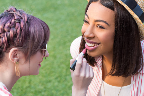 muchachas multiétnicas aplicando maquillaje
 - Foto, imagen