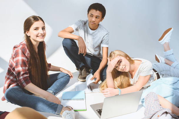 adolescentes sonrientes multiétnicos con computadora portátil
 - Foto, Imagen