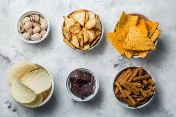 Salty beer snacks in whit bowls - Photo, image