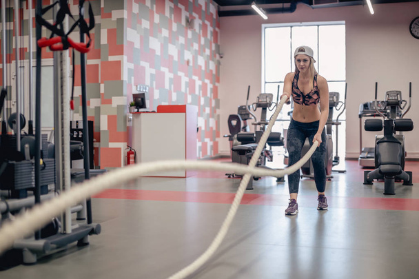 Athletic young woman doing some cross fit exercises with a rope - Foto, imagen