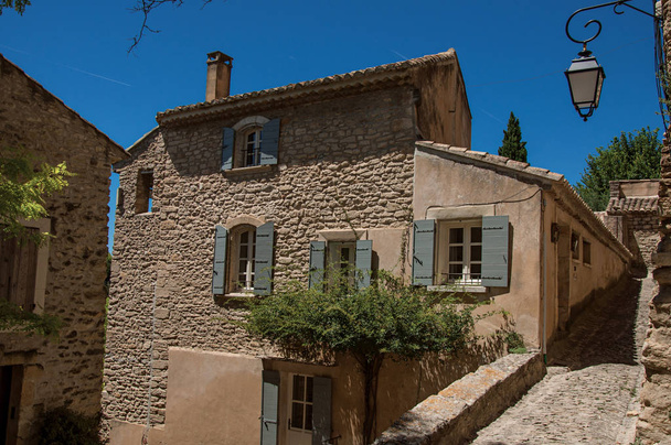 View of typical stone houses and wall with sunny blue sky, in alley of the historical city center of Gordes. - Photo, image