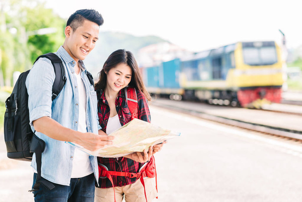 Ευτυχισμένο ζευγάρι ταξιδιώτη κρατώντας ένα χάρτη στο σιδηροδρομικό σταθμό - Φωτογραφία, εικόνα