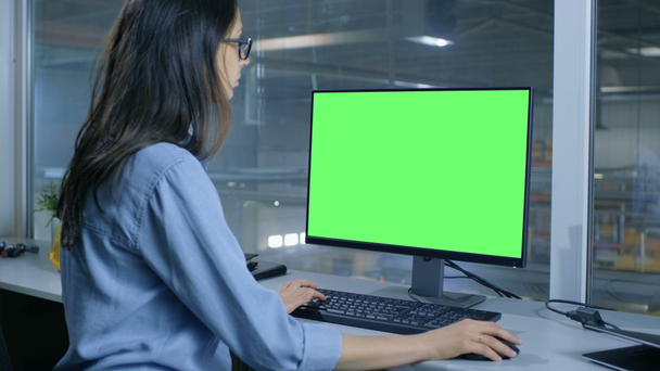 Ingénieur industriel féminin travaille sur son ordinateur avec écran vert maquillé. L'intérieur de l'usine est vu de sa fenêtre de bureau
. - Séquence, vidéo