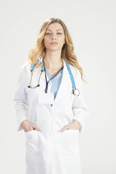 Female doctor in white surgical coat and stethoscope standing isolated on white background - Photo, image