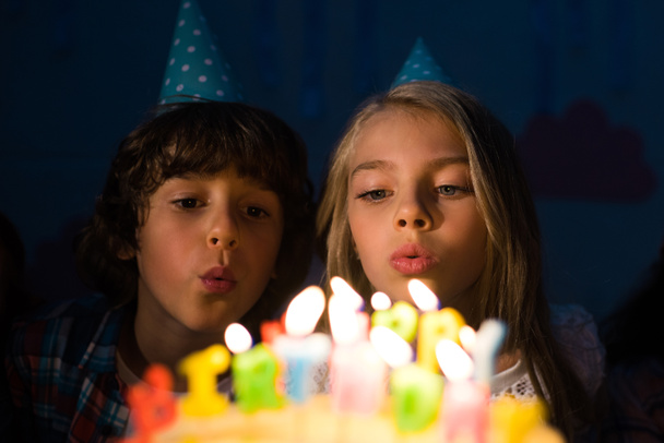 kinderen blazen kaarsen op de verjaardagstaart - Foto, afbeelding